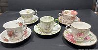 Photo showing 5 pairs of Royal Albert teacups and saucers with varied floral hand painted designs and gold trim.
