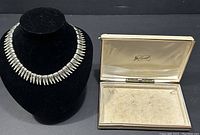 Photo showing the Coro Cleopatra gold tone choker necklace on a black bust next to its original box with velvet lining.