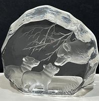 Clear crystal paperweight with detailed engraving of a wolf with two cubs and tree branches.