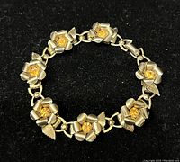 Full view of the gold plated Coro bracelet with floral and leaf motifs, orange rhinestones centered in flowers.