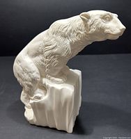 Right side view of creamy white polar bear sculpture with textured fur sitting on a block base.
