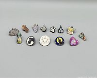 Full view of 12 different Disney-themed pins in varying colors and designs on white background.