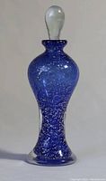Front view of hand blown blue glass perfume bottle with bubble shaped clear stopper in place.