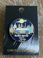 Photo of the limited edition Hard Rock 50th anniversary slider collector pin on black card backing.