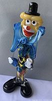 Front view of 9-inch tall Murano glass clown figurine with vibrant colors, black top hat, and oversized shoes.