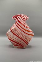 Side view of the vase showing candy cane swirl red, orange, white stripes and flared top