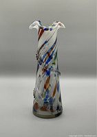 Front-side view of tall Murano glass vase showing multicolor swirl splatter pattern with applied spiral glass decoration and ruffled top rim.