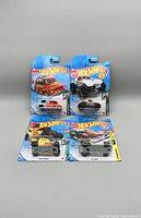 Five Hot Wheels die-cast cars in original packaging arranged in two rows on a white background.