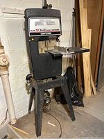 Full view of Craftsman Sears 12" Band Saw Sander standing on its metal base in basement with wall and wood planks behind.