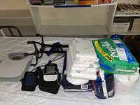 Lot showing Depends adult diapers, blood pressure cuffs, walker cane, picker tool, and scale together