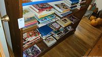 Books stacked and arranged on a wooden bookshelf, showing a variety of titles and sizes.
