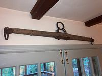 Antique wooden double tree yoke mounted above doorway, showcasing wood texture and iron hardware attachments.