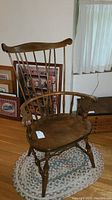 Front view of vintage Nichols & Stone wooden armchair placed on a braided rug.