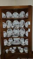 Full view of the wooden shelves displaying multiple pieces of Royal Doulton Arcadia china including plates, cups, saucers, and bowls.