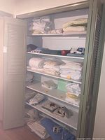 Closet shelves containing folded towels, sheets and other linens in various colors and patterns including white, yellow and floral
