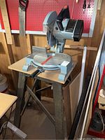 Front and angled side view of Delta Model 34-080 mitre saw mounted on a metal stand, showing circular blade and motor housing.