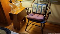 Handmade wood faux drop leaf table next to Nichols & Stone Co. wooden chair with cushions.