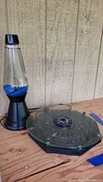Lava lamp next to octagonal glass Tree of Life themed Ouija board, showing overall lot contents.