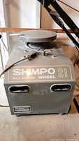 Front view showing SHIMPO 21 metallic traction drive label, rectangular green steel housing, vent slots and power cord.