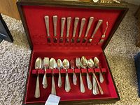 Top view of the wooden box with silver plated spoons and forks arranged in red felt slots
