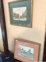 Two smaller framed cityscape prints displayed on wall and shelf, showing size and framing details