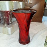 Front view of one red glass vase showing the flared shape and blackened rim