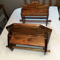 Two wooden paper towel holders on a white surface with visible grain and side knobs, viewed from the top and front sides.