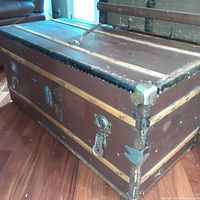 Front and side view of vintage steamer trunk showing wood panel construction and metal corner reinforcements
