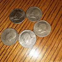 Top side of five 1971 U.S. Kennedy half dollar coins showing obverse portrait and inscriptions.