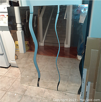 Photo showing three wavy edge mirrors standing against a blue wall and reflecting tiled floor and staircase.