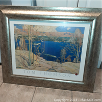 Full view of framed Tom Thomson print showing landscape with lake, trees, and snow, with artist name below the image.