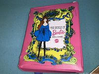 Closed pink vinyl 'The World of Barbie' doll case with illustrated Barbie figure and Mattel logo.