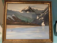 Front view of the framed Canadian oil on canvas painting showing a mountain landscape with snow-capped peaks and reflection in the water.