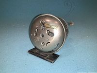 Back view of the round clock showing adjustment knobs, metal stand and 'Made in Canada by Clockwerks' label with Roger Wood signature.