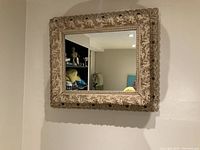 Wall mounted square mirror with detailed carved frame in beige/cream color.