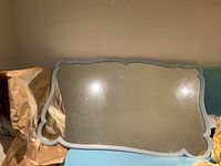 Front side view of the large rectangular mirror with scalloped edges and baby blue painted maple wood frame showing some wear marks on the mirror surface.