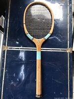 Photo of the first wooden tennis racquet with intact strings and turquoise accents