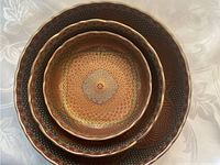 Stacked view showing the three metal decorative bowls with detailed patterned interiors and scalloped edges.