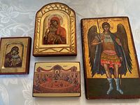All four icons displayed on a tablecloth background: small square Virgin Mary icon, arched Virgin Mary icon, Last Supper icon, and Archangel Michael icon