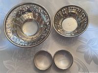 Photo showing all four Birks sterling silver items: two small bowls and two napkin rings.