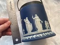 Side view of biscuit barrel showing cobalt blue jasperware with white relief classical figures and applied EPNS rim and handle; ruler held showing approximate height of about 4.75 inches