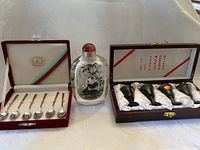 Photo showing boxed spoon set, panda bear decorated perfume bottle, and boxed polished stone cordial cups.