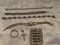 Photo shows all 7 pieces: 4 bracelets, 1 brooch, 2 pendants, arranged on textured surface.