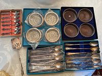 All items displayed: parfait spoons, coasters, ashtrays, serving tongs, coffee spoons in original boxes and protective packaging.