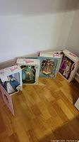 Four Barbie dolls in original Mattel packaging on hardwood floor
