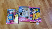Set of three Barbie Career Collection dolls in original packaging displayed on wooden floor.