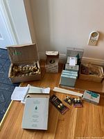 Wide view of lot showing multiple boxes of Party Lite candles and the box with three brass colored twisted spiral candle holders.