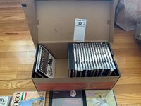 Photo of box full of assorted CDs showing box exterior and some CDs arranged upright inside.