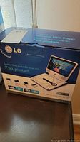 Photo of the LG portable DVD player original box showing front view with the player image and features such as 7-inch swivel LCD.
