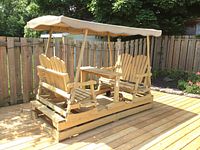 Front angle of assembled glider patio set on wooden deck showing benches, center table, and canopy